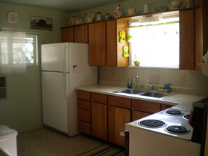 A compact kitchen with wooden cabinets, a white refrigerator, a sink, and a stove. - Zion and Bryce Canyon Getaway (Glendale)