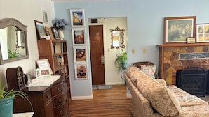 A room with a wooden floor, a sofa, a dresser, a mirror, and a fireplace. - Zion and Bryce Canyon Getaway (Glendale)