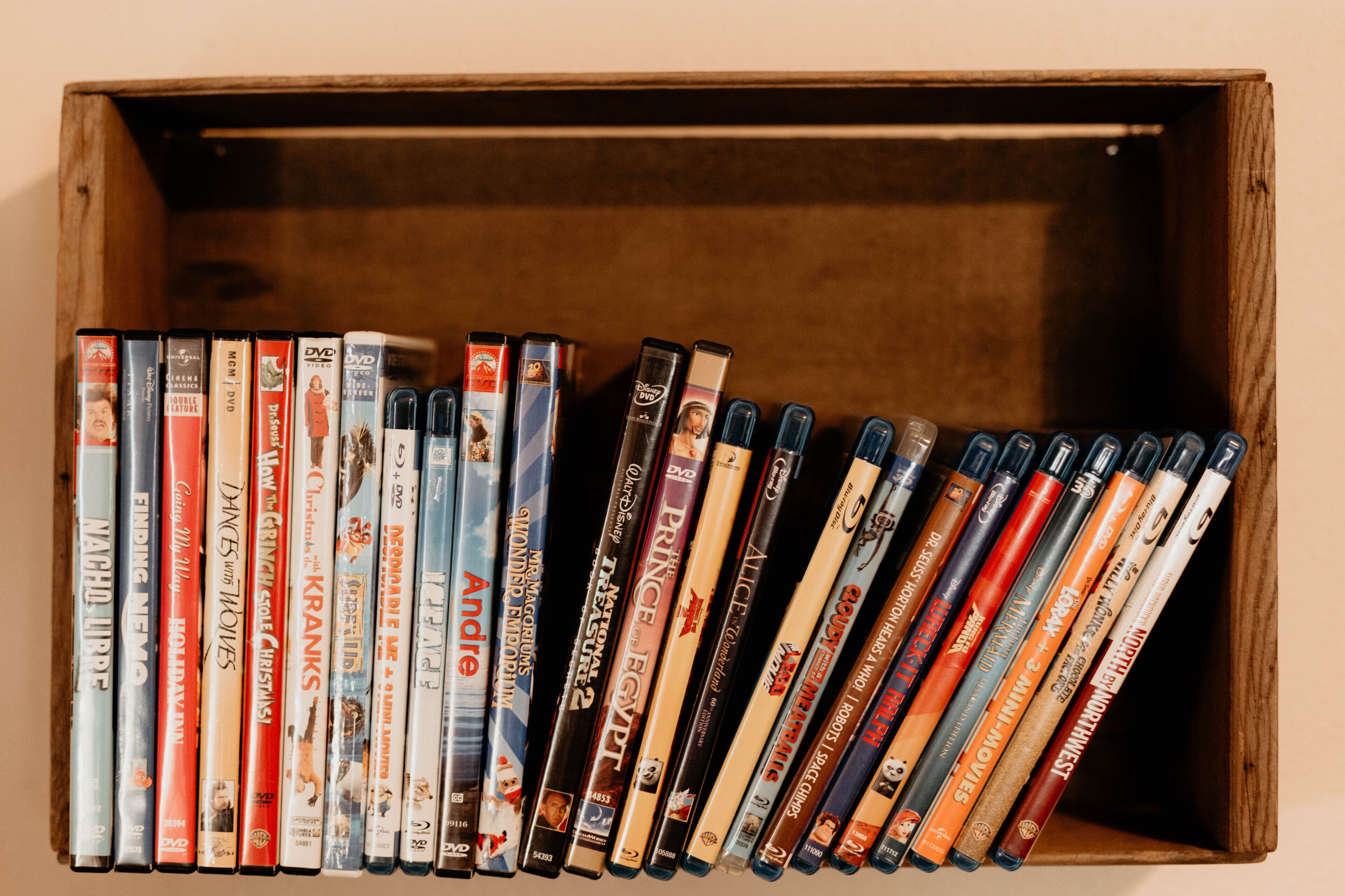 A wooden box containing DVDs with visible titles and labels.