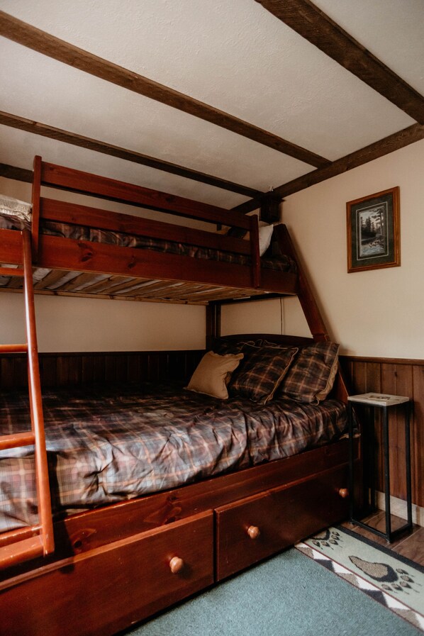 A bunk bed with a wooden frame and a lower bed with a plaid bedspread. - Cozy Creekside Cottage (Custer)