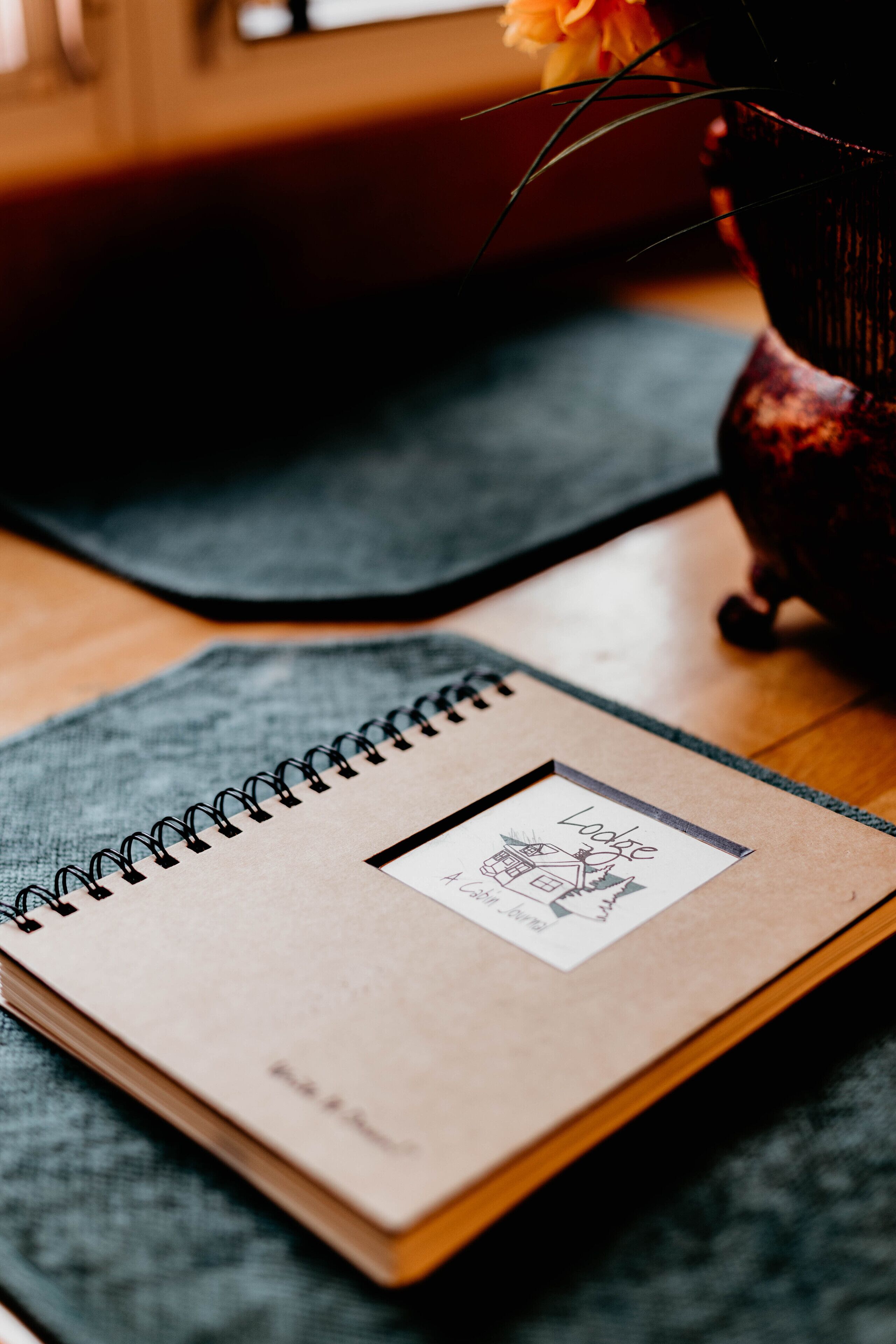 Un cuaderno de espiral con un dibujo en la portada, sobre un tapete con textura.
