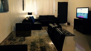 A living room with a sofa, a coffee table, and a flat-screen TV. - 2 bdrm 1 ba PRIVATE APT-close to NAVY BASE-SAVE MONEY Book now! Free internet (Sinajana)