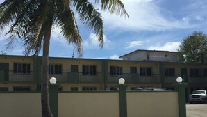 A multi-story building with a green and beige facade, a palm tree in the foreground, and a clear sky. - 2 bdrm 1 ba PRIVATE APT-close to NAVY BASE-SAVE MONEY Book now! Free internet (Sinajana)