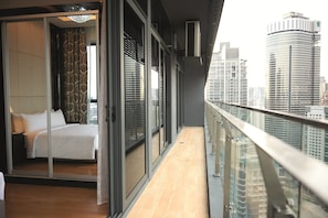 Ein modernes Hotelzimmer mit einem großen Bett, Schiebegläsern und Blick auf die Stadt.