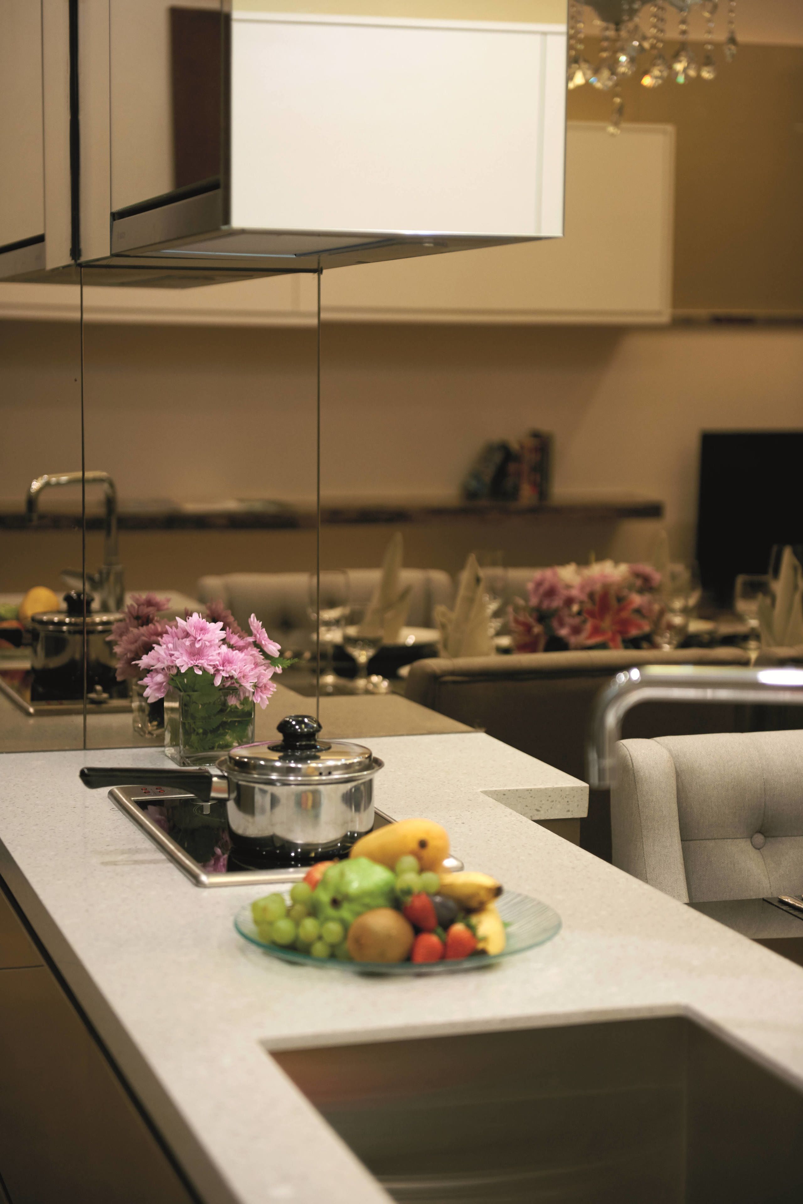 A modern kitchen with a central island, a sink, and a dining area with a sofa and table.