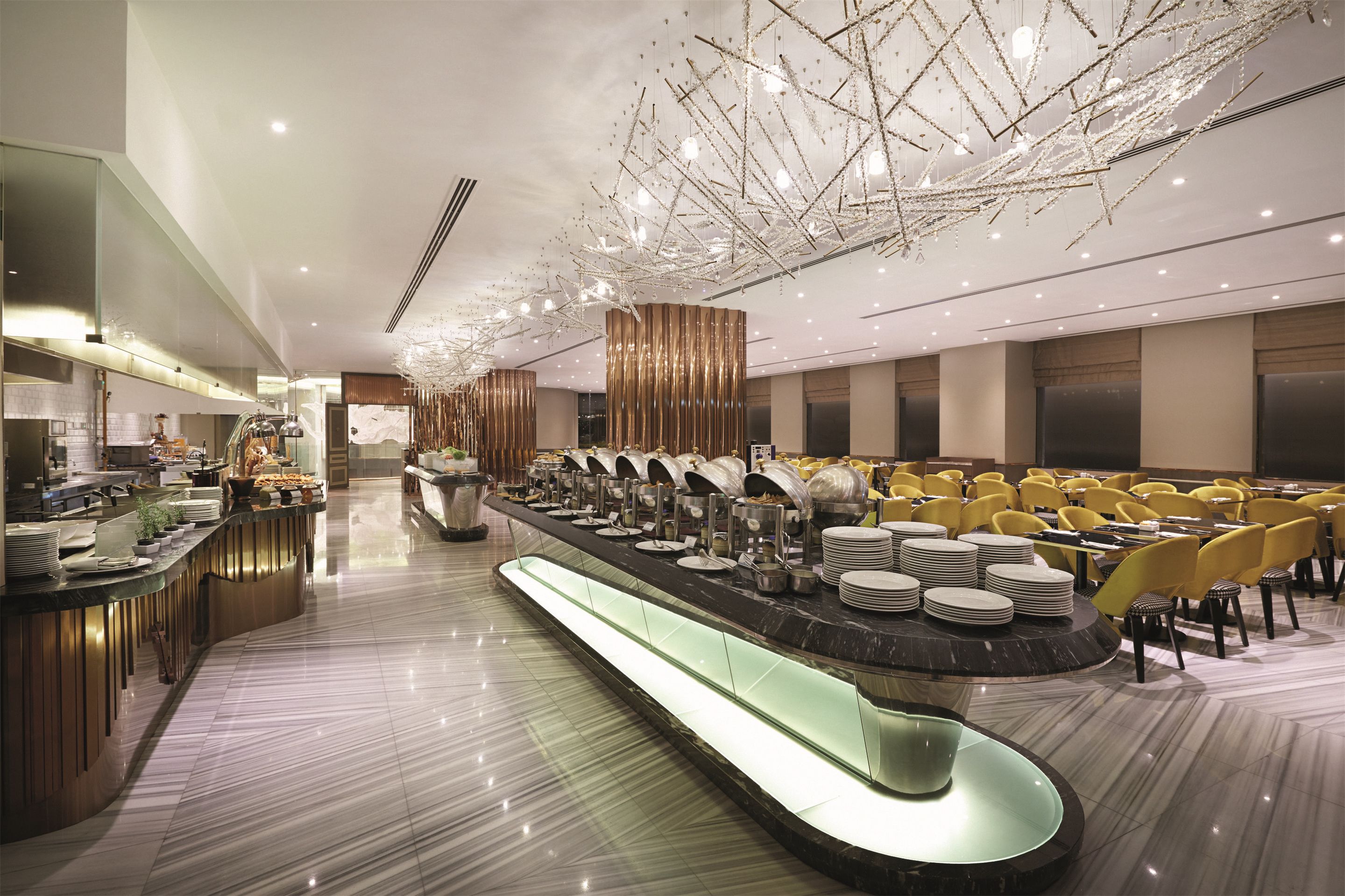 A modern hotel lobby with a long reception counter, seating area, and a decorative ceiling.