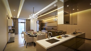 A modern kitchen with a central island, a dining area with a chandelier, and a living space with a sofa and curtains. - Dorsett Residences Bukit Bintang at Dorsett Kuala Lumpur (Kuala Lumpur)