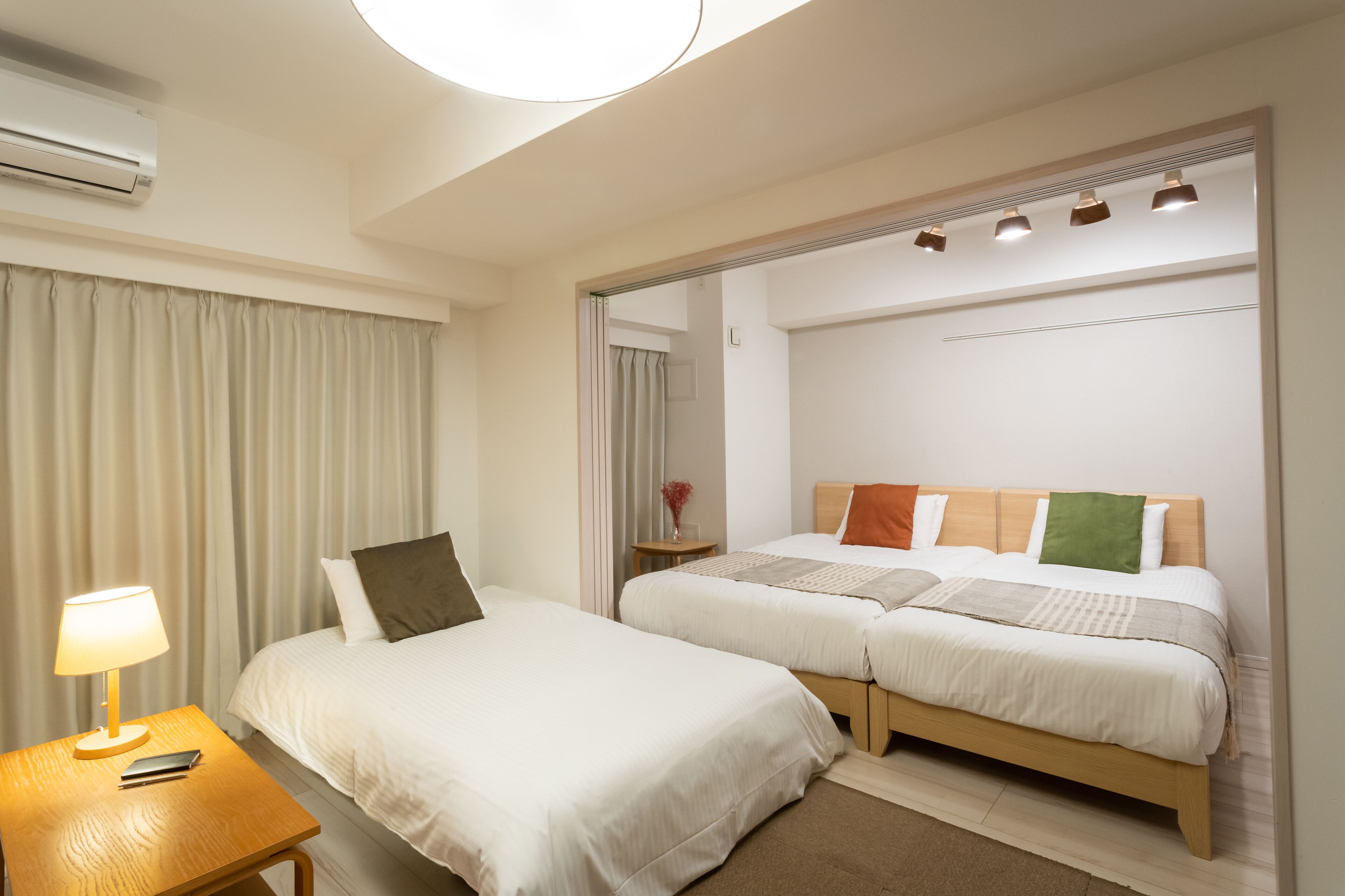 Une chambre d’hôtel avec deux lits, une table de chevet avec une lampe et un miroir.