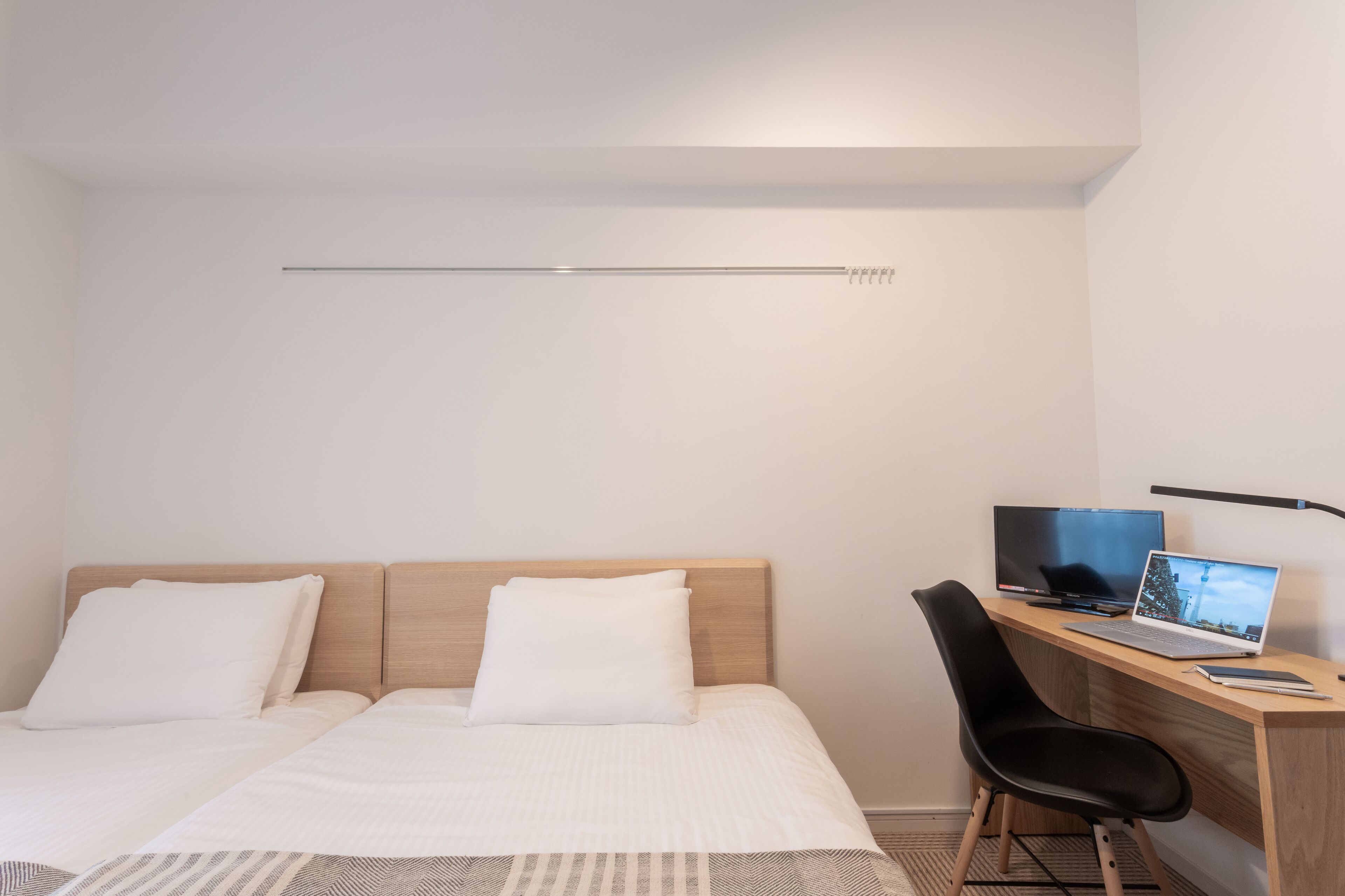 Una camera da letto con un letto, una scrivania con un portatile, una sedia e una televisione.