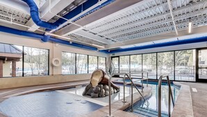 An indoor swimming pool with a hot tub, clear windows, and a view of the outside. - Paradise Meadow by Ski Colorado (Breckenridge)