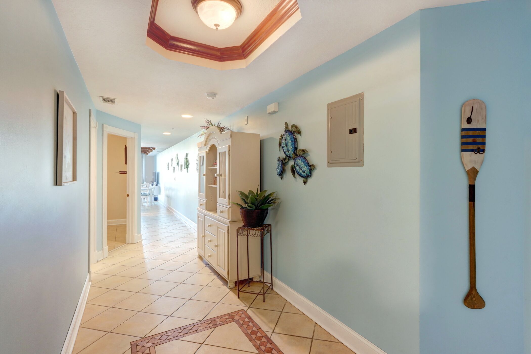 A hallway with light blue walls, a white cabinet, and a wooden paddle on the wall.