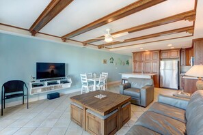 Un salon moderne avec une table basse en bois, un téléviseur et un coin repas avec des chaises.