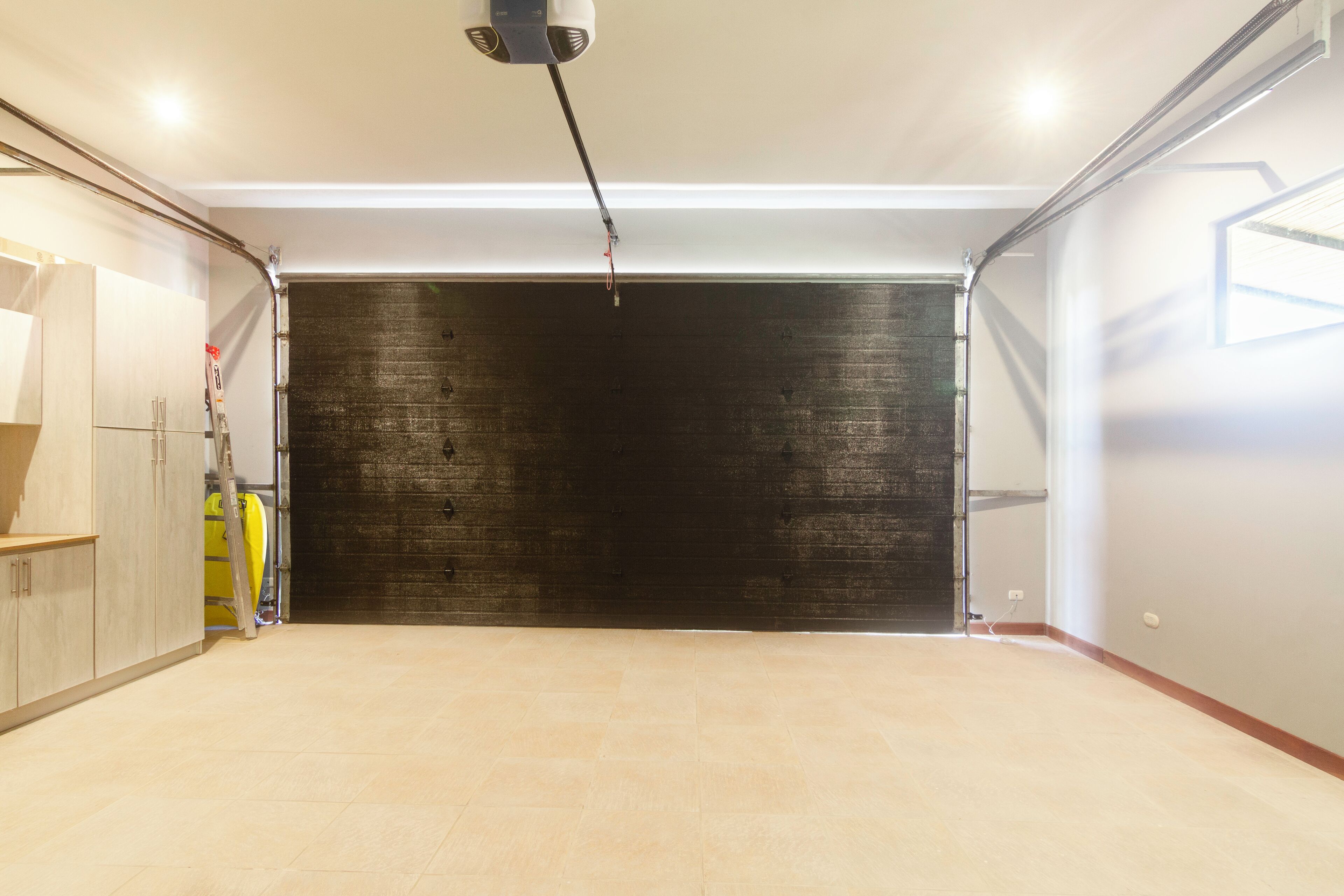 A garage with a dark wooden wall, a light-colored floor, and a ceiling fan.
