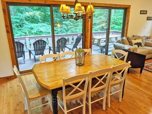Enjoy meals in a serene setting with a large table surrounded by comfortable chairs and a view of lush greenery.