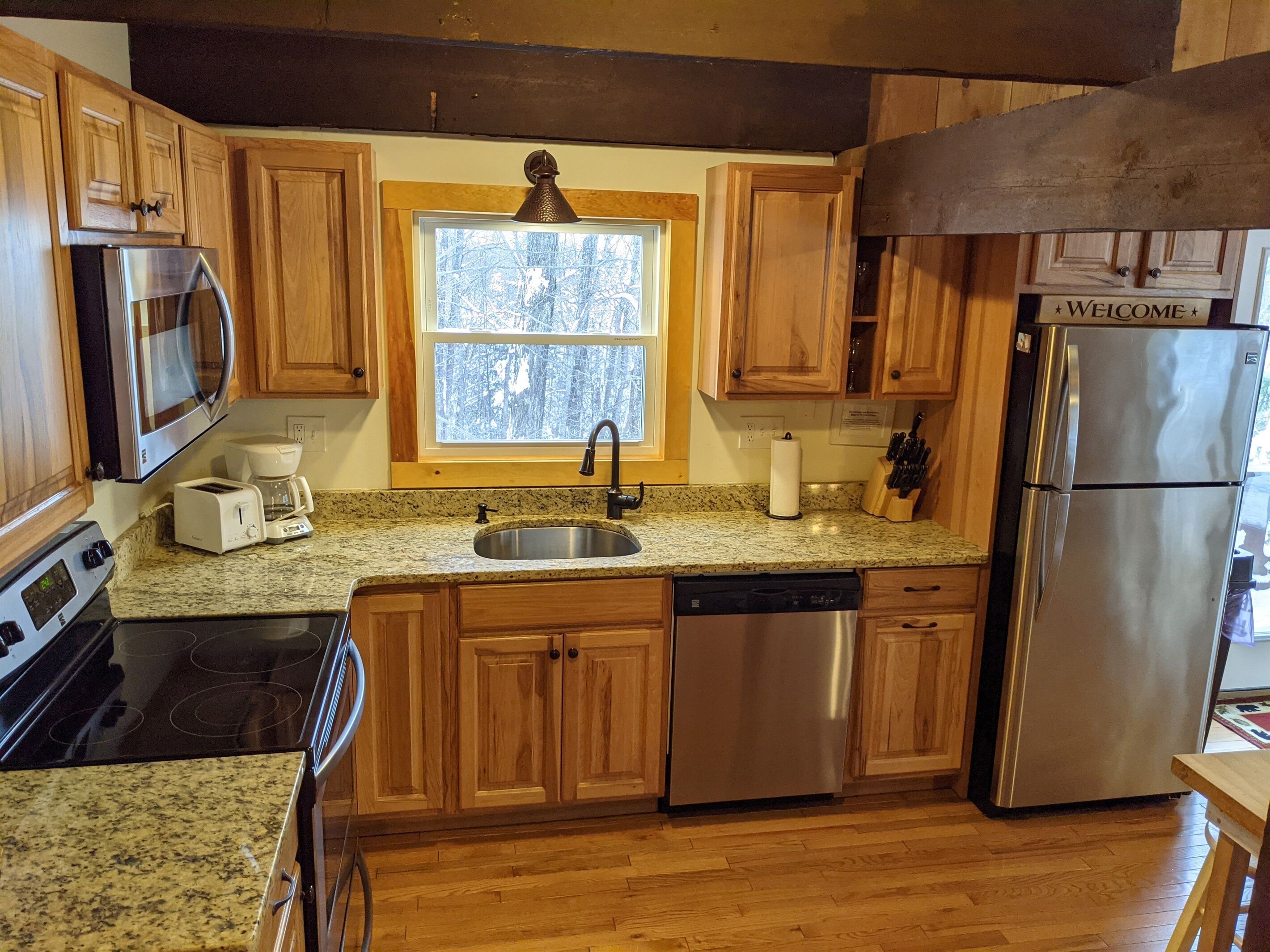 A kitchen with wooden cabinets, a stainless steel refrigerator, a microwave, a coffee maker, and a dishwasher.