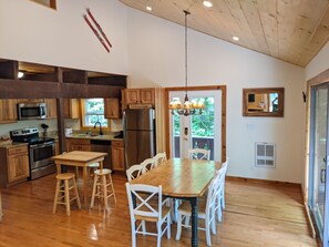 A spacious kitchen with wooden cabinets, stainless steel appliances, and a large dining table with white chairs.