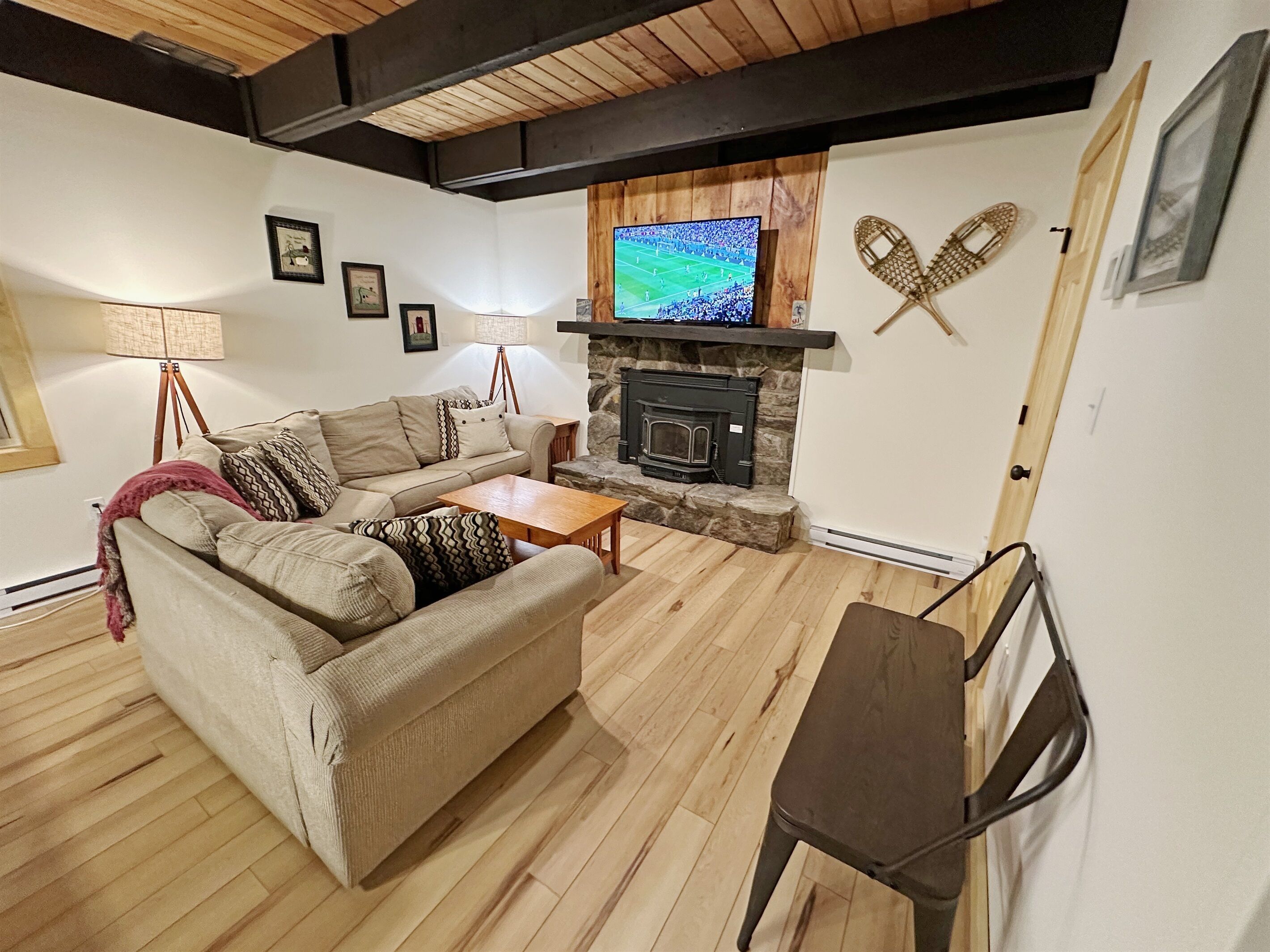 A cozy living room with a sofa, a coffee table, a fireplace, and a television mounted above it.