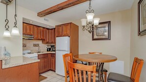 Una cocina con armarios de madera, un refrigerador blanco, una estufa y una mesa de comedor con sillas.