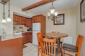 Una cocina con armarios de madera, un refrigerador blanco, una estufa y una mesa de comedor con sillas.