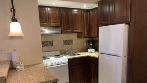 A kitchen with wooden cabinets, a white refrigerator, a stove, and a sink.