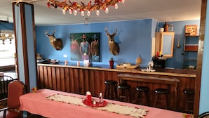 Un restaurant doté d’un bar en bois, d’une salle à manger aux tables recouvertes de nappes rouges et ornée de têtes de cerf fixées au mur.