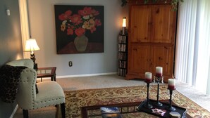 A living room with a floral painting, a wooden cabinet, a leopard print chair, a coffee table with candles, and a lamp. - Yacht Club, Golf course, lake view, ground floor condo (Montgomery)