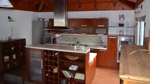 Una cocina con armarios de madera, una campana de acero inoxidable, una bodega y una isla integrada con un fregadero.