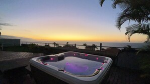 Un jacuzzi con vistas a la puesta de sol sobre el océano.