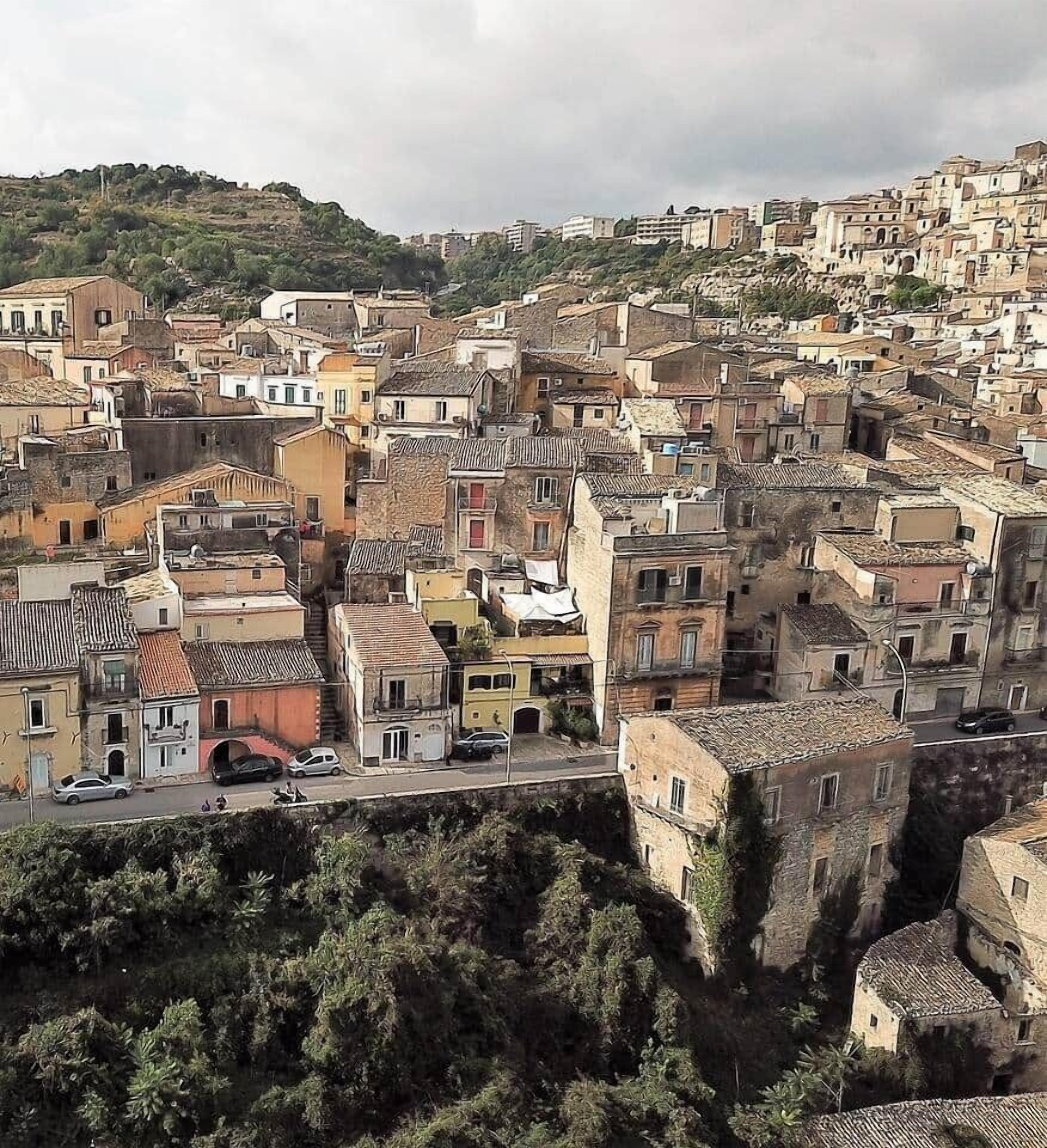 A densely packed urban area with closely built structures, narrow streets, and a prominent historical building with a fortified wall.