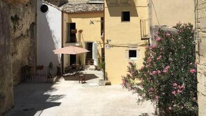 A narrow alleyway with buildings on either side, a small outdoor seating area with tables and chairs, and a staircase leading to an upper floor. - Old Market House Antò Ragusa (Ragusa)
