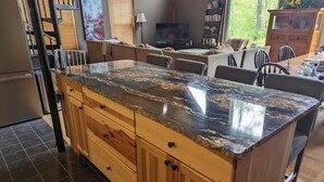 Una cocina con una isla grande, armarios de madera y piso de baldosas.