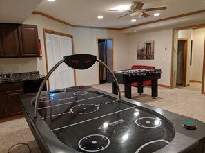 Quarto com mesa de futebol, esteira e espaço de cozinha.