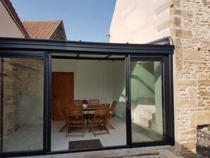 A dining area with a table and chairs, a wooden door, and a stone wall. - Burgundy charming house - countryside, tourism, garden and sauna (Vassy-Sous-Pisy)