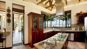 A spacious kitchen with a large island, wooden cabinets, and a view of the beach. - Deluxe Beach Front Luxury Villa - Private Pool in Gated Community! (Playa Hermosa)