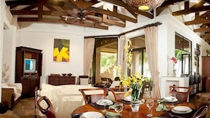 A spacious room with a large bed, a dining table set for four, and a television in the corner. - Deluxe Beach Front Luxury Villa - Private Pool in Gated Community! (Playa Hermosa)