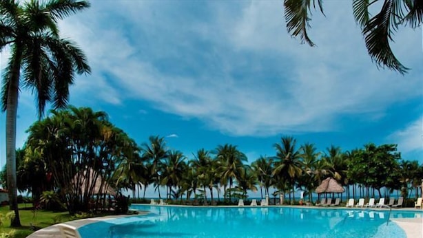A pool with lounge chairs and palm trees, surrounded by a clear sky. - Deluxe Beach Front Luxury Villa - Private Pool in Gated Community! (Playa Hermosa)