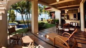 A covered outdoor seating area with wicker furniture, a pool, and a view of the ocean. - Deluxe Beach Front Luxury Villa - Private Pool in Gated Community! (Playa Hermosa)