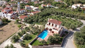 Une vaste villa dotée d’une piscine, entourée d’une végétation luxuriante et située dans un paysage vallonné.