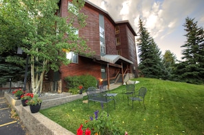 A modern building with a sloped roof, outdoor seating, and a well-maintained lawn. - Cimarron Chalet (Breckenridge)
