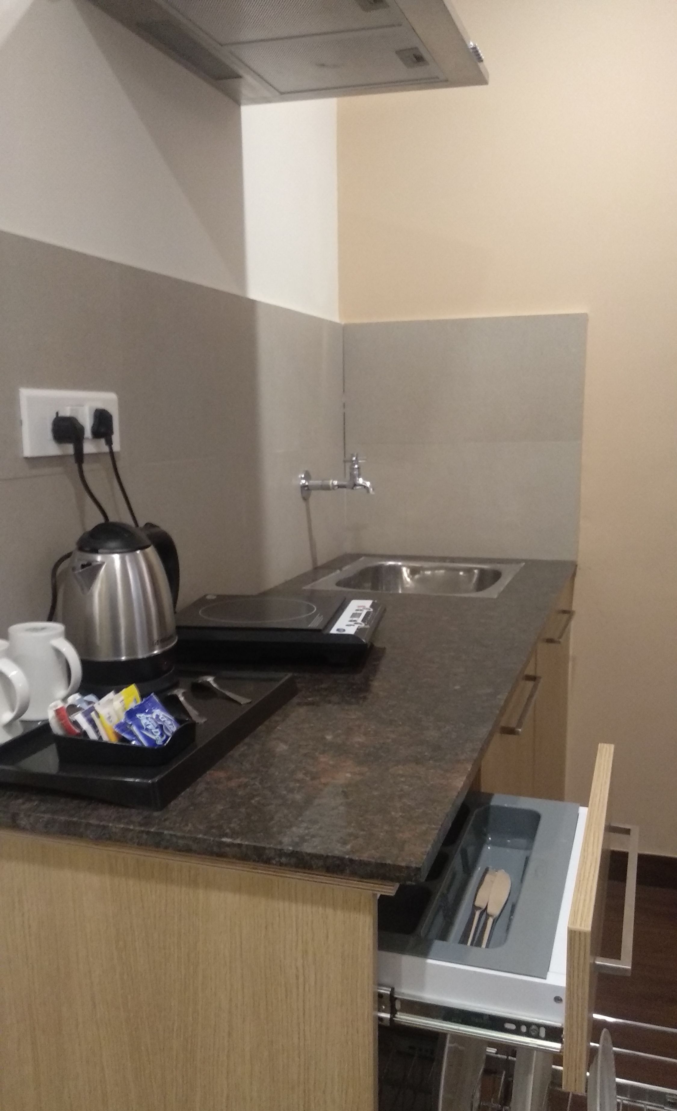 A compact kitchen with a built-in oven, a kettle, and a coffee maker on the counter.