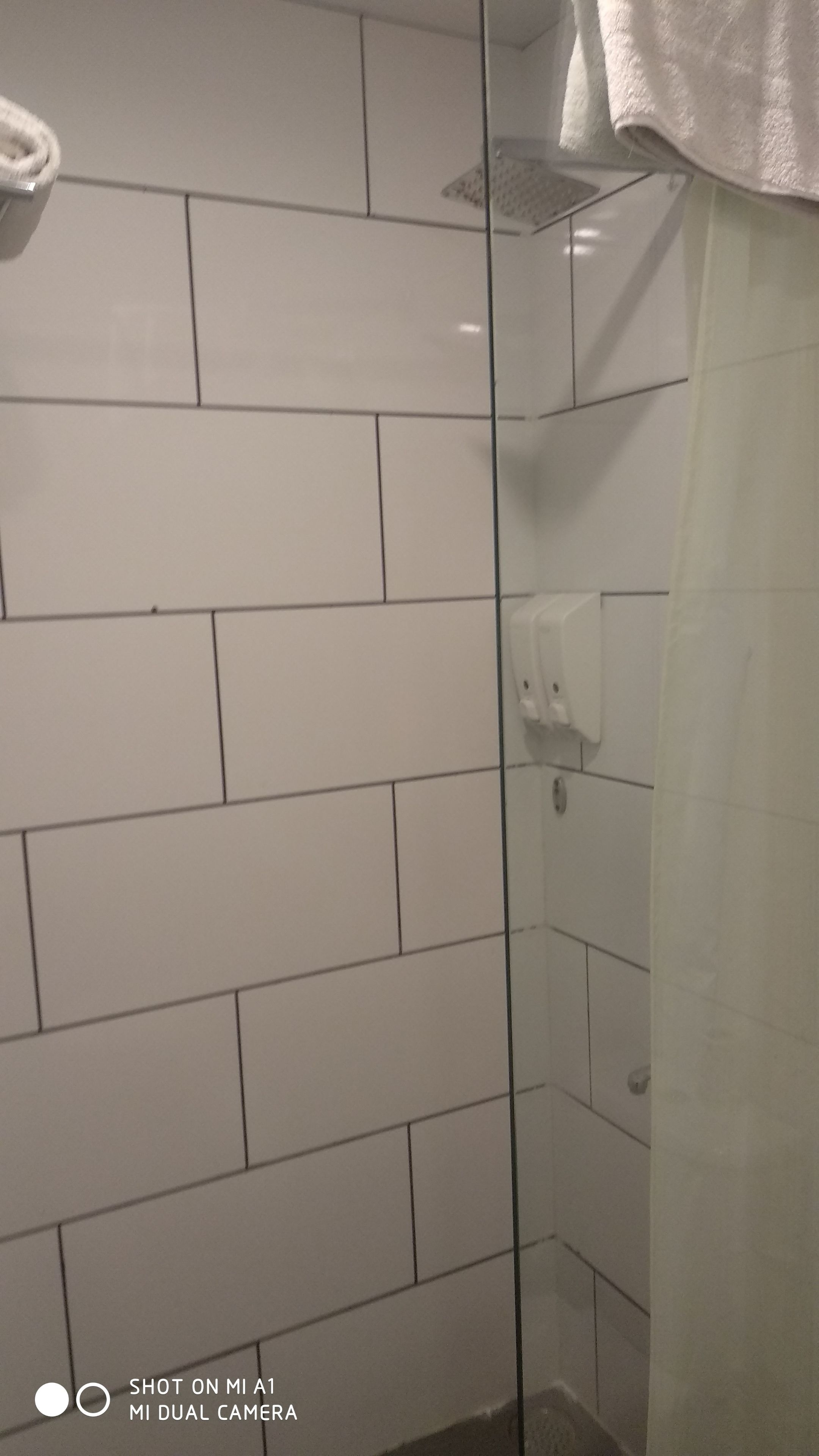 Un bagno con pareti piastrellate di bianco e cabina doccia in vetro.
