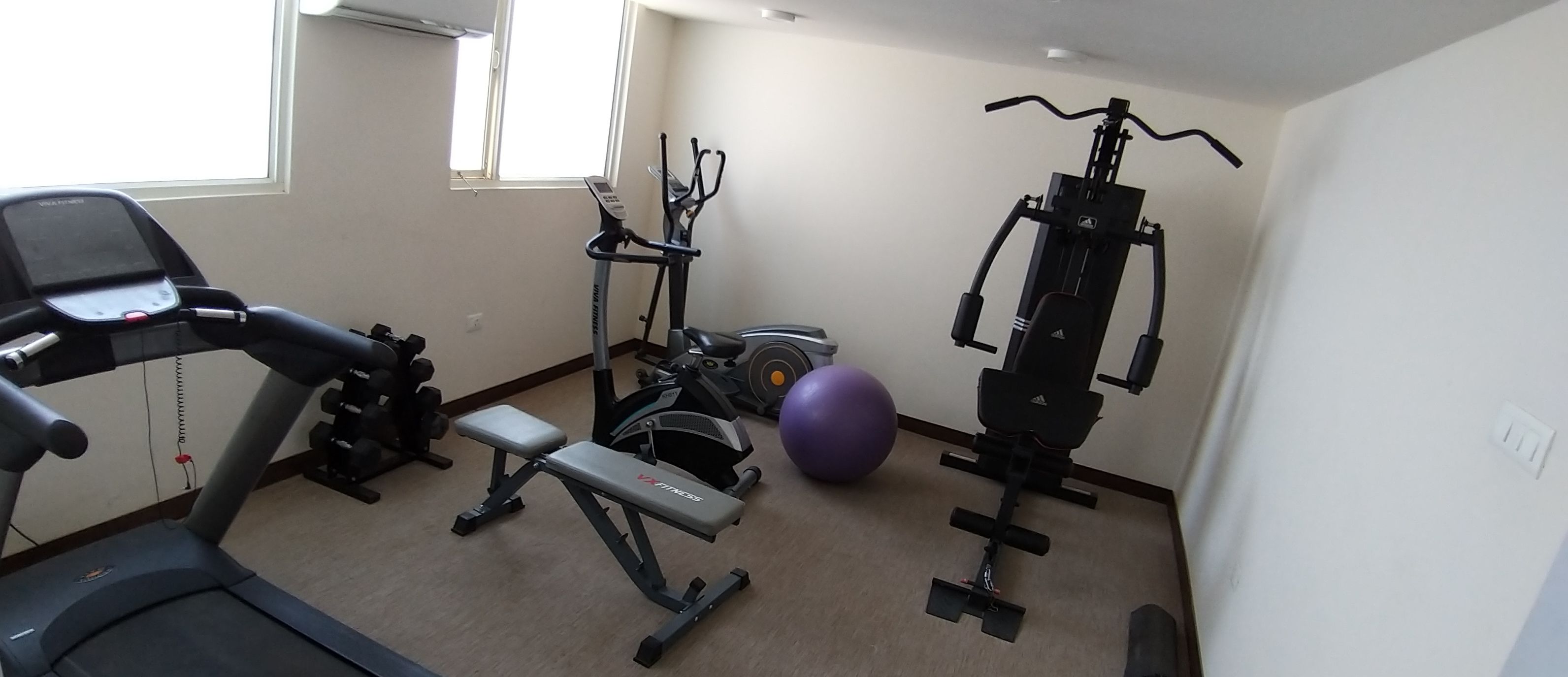 A home gym with a treadmill, elliptical, stationary bike, and weight bench.