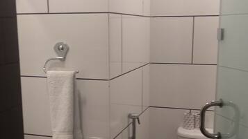 Un baño con lavamanos, inodoro y ducha blancos.