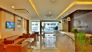 A hotel lobby with a reception desk, seating area, and a large window offering a view of the building. - Starlit Suites Neemrana (Neemrana)
