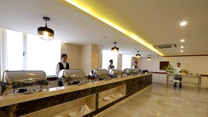 A buffet setup with multiple self-service stations, a reception area, and a clean, modern interior. - Starlit Suites Neemrana (Neemrana)