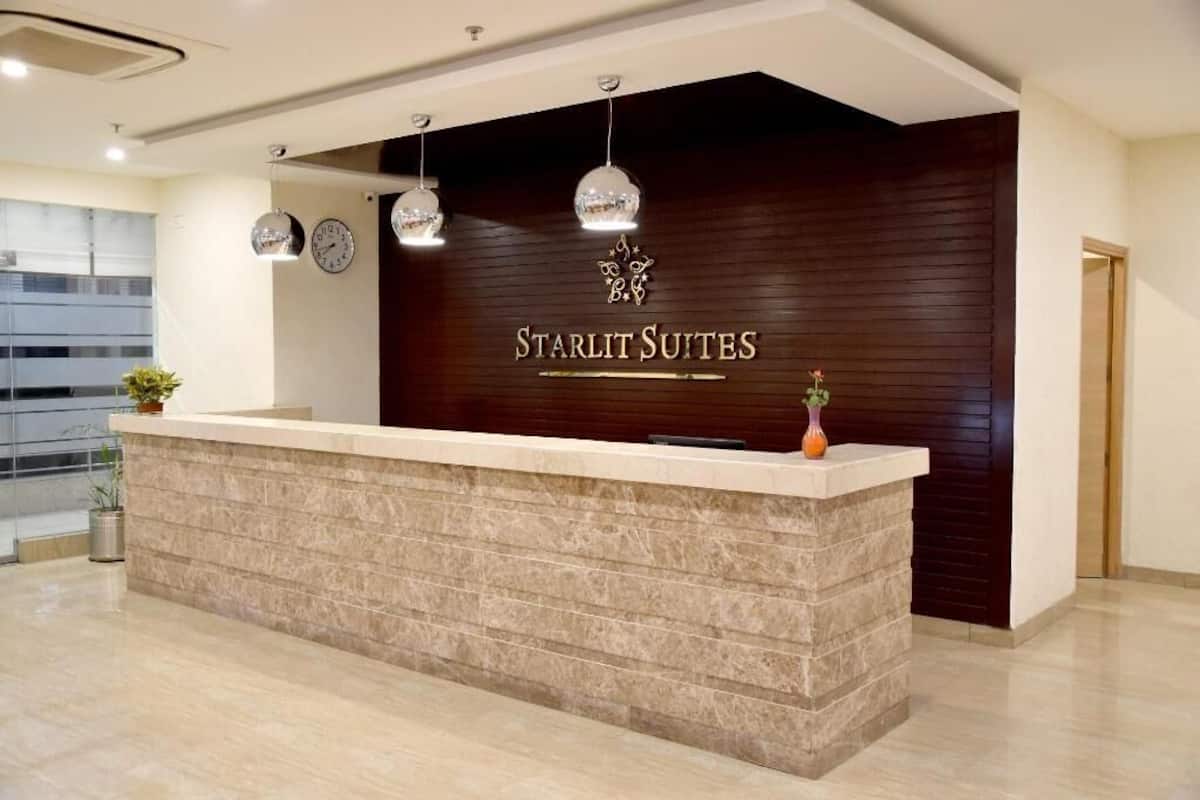 A reception desk with a dark wood backdrop, a clock, and a sign reading 'Starlit Suites.'
