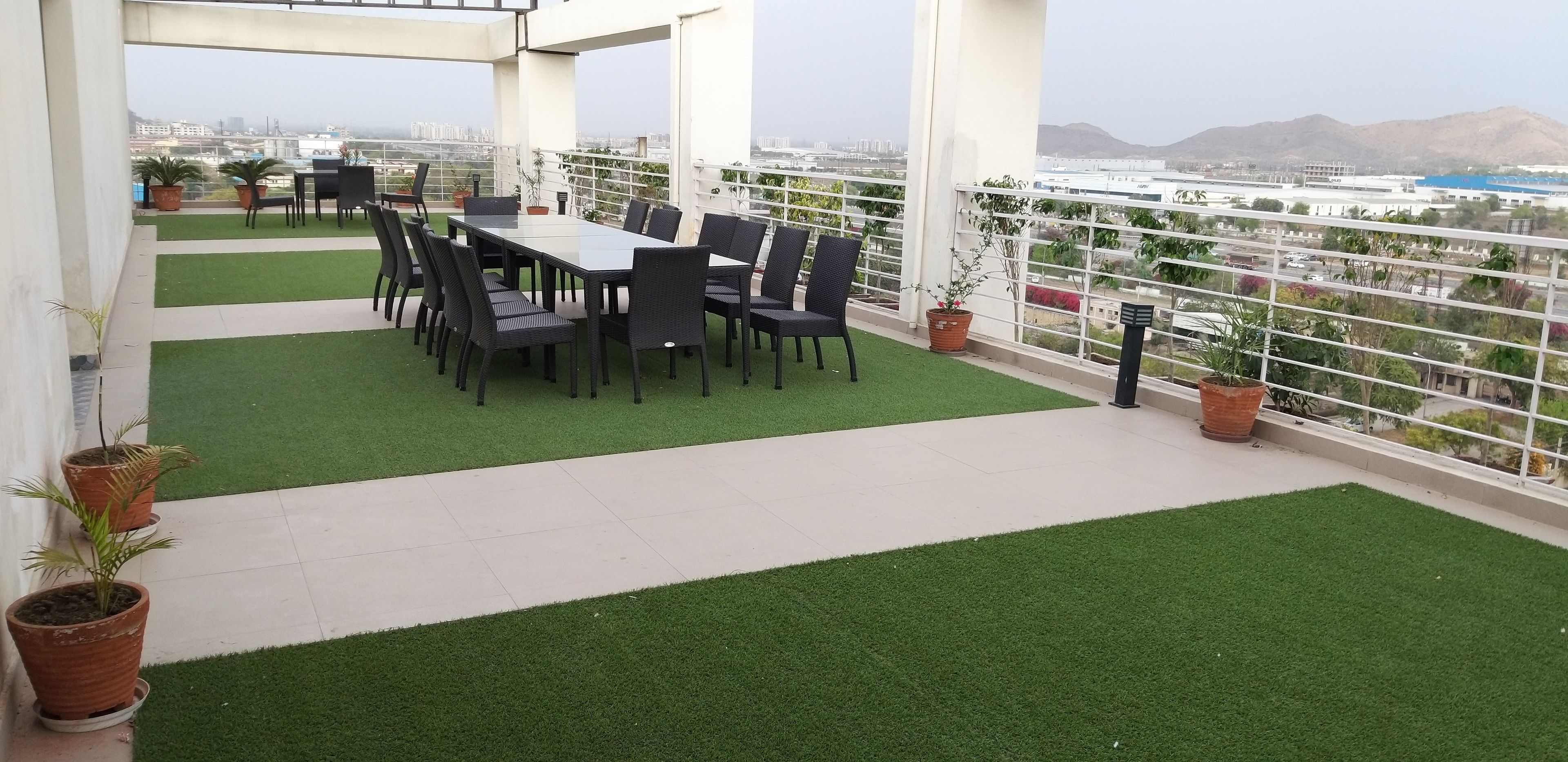 Een dakterras met een eettafel en stoelen, omringd door potplanten en uitzicht op de stad.