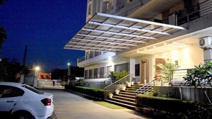 A modern building with a covered entrance, a staircase, and a parking area. - Starlit Suites Neemrana (Neemrana)