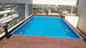 Una piscina al aire libre, sillones reclinables de piscina