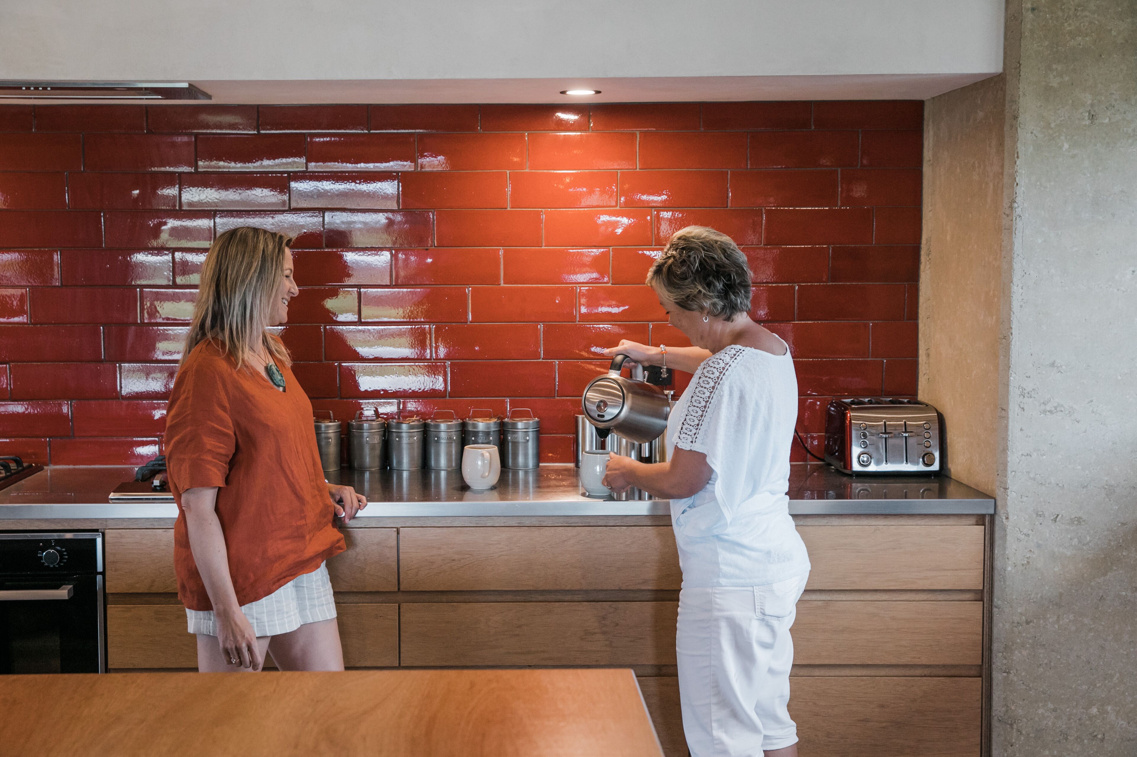 A kitchen with red brick backsplash, stainless steel appliances, and wooden cabinets.
